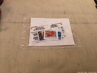 Plastic sleeve containing several mint Canadian stamps including 12¢ sailing ship, 15¢ maple leaf and others