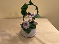 Full view of rotating hummingbird music box on beige surface