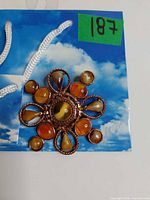 Front view of brooch showing copper metal and amber cabochons