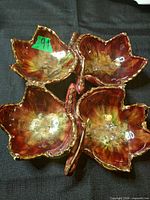 Top view of ceramic dish showing four leaf bowls joined with handle, red/green glaze and gold rims visible