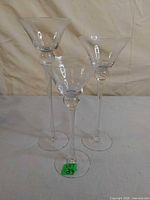 Three tall clear martini-style glass candle holders side view