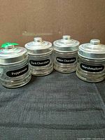 Front view of four labeled glass jars with metal lids