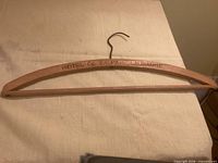 Full view of wooden coat hanger showing engraving and metal hook