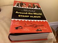 Front view of hardcover Illustrated Around-the-World Stamp Album showing cover art and spine thickness