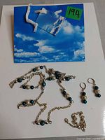 Necklace, anklet, earrings and small gift bag displayed on white background