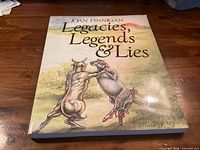 Front cover of the paperback book Legacies, Legends & Lies by Joan Finnigan on wooden surface