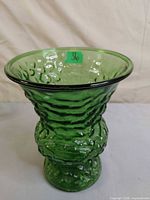 Full view of green textured glass vase, flared rim, pedestal base