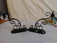 Front view of both black metal scrollwork wall sconces standing side by side