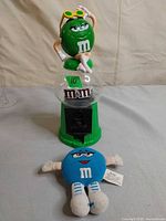 Front view of green candy dispenser and blue plush