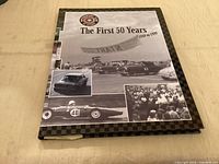 Front cover of hardcover book titled The First 50 Years 1949-1999 with racing images