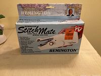 Front of boxed Remington Stitch Mate handheld sewing machine