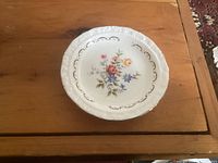 Front view of saucer showing floral design and scalloped gilt edge