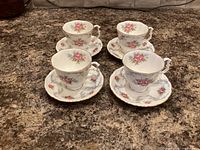 Four demitasse cup and saucer sets displayed on countertop