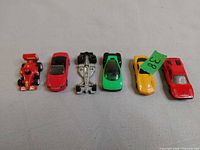 Six toy cars lined up side by side