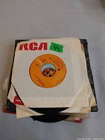 Stack of 45 rpm records, top sleeve RCA with orange label disc