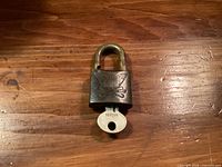 Front of brass padlock showing embossed eagle logo and key inserted