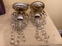 Front view of both hanging lamps showing metal canopies, ribbed sockets, and crystal prism strands