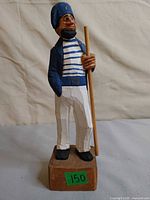 Front view of painted wooden sailor carving on block base