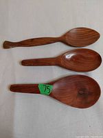 Top view of three assorted wooden salad spoons on light surface