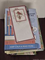 Stack of various unused stationery items showing list pad, journal kit, other notebooks