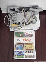 Console, power adapter, A/V cable, sensor bar, Wii Play game case visible
