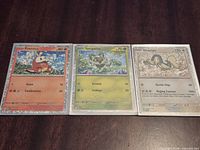 Front view of three holo Pokémon cards Fuecoco, Sprigatito, Drampa in sleeves