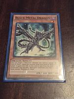 Front of Black Metal Dragon card inside blue sleeve showing title, artwork and text
