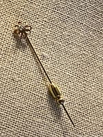 Full view of gold stick pin with floral head and clutch