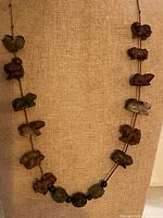 Full view of necklace on display bust showing arrangement of carved animal beads and accent beads