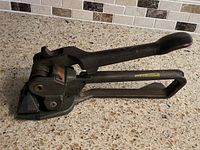 Left side view of Signode tensioner showing main body, handle, and strapping channel