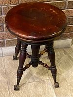 Full view of piano stool showing seat, legs and claw glass feet