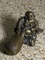 Full view of bronze Laughing Buddha figurine showing sack and seated pose