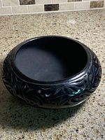 Top view of black clay bowl showing interior and carved exterior