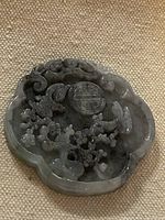 Front view of gray jadeite pendant showing relief carving details