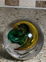 Full view of glass paperweight showing green and yellow swirl