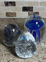 Front view of three glass paperweights showing colors and forms