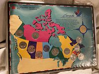 Obverse side showing coins mounted in coloured Canada map display