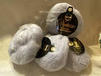 Four labelled balls of light grey mohair yarn