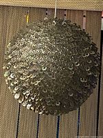 Full view of sequin sphere hanging, showing overall shape and surface