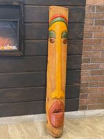 Full view of carved wooden mask leaning against wall