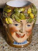 Front view showing face, leaf crown, Prosit cartouche