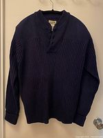 Front view of navy rib-knit pullover sweater hanging