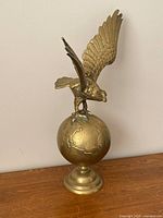 Front angled view of brass eagle on globe sculpture