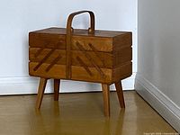 Front angled view of wooden cantilever sewing box on legs