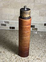 Full view of cylindrical wood pepper mill standing upright