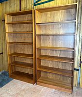 Full frontal view of both teak bookcases showing overall design and shelf configuration