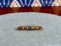Front view of brooch showing sapphire, seed pearls, lattice design