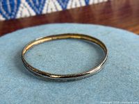 Full view of sterling silver bangle on blue surface