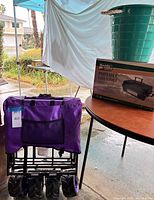 Folded purple wagon, boxed Boulder Creek grill on table, teal tub partially visible
