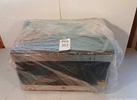 Microwave wrapped in protective plastic, full view